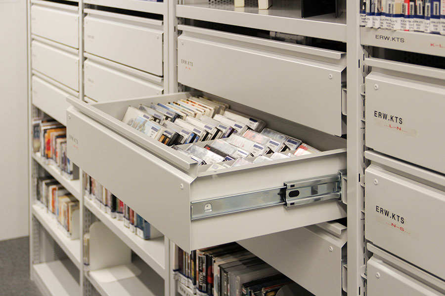 Hörbücher und CDs einsortiert in eine Lade des Bibliotheksregals
