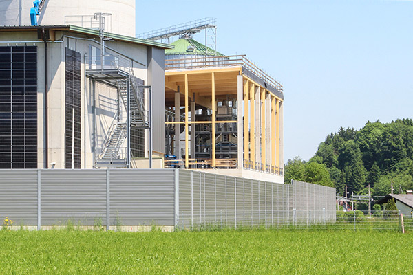 Schallschutzwand vor einem Industriebetrieb der die Anwohner vor den Lärmemisionen schützt.